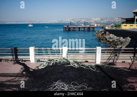 Pile de filets de pêche sur la jetée. Vue sur la jetée avec des bateaux de pêche dans la ville de Valparaiso, Chili. Yachts dans la baie. Vue sur les collines de la ville de Valparaiso Banque D'Images