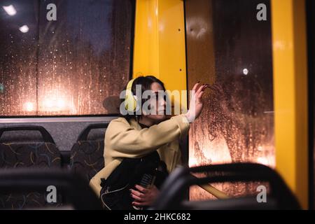 Jeune femme tirant sur la fenêtre en voyageant dans le trolley-bus Banque D'Images