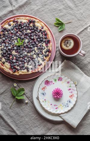 Tarte au cassis, une tasse de thé au citron et des assiettes de fleurs de dahlia. Banque D'Images