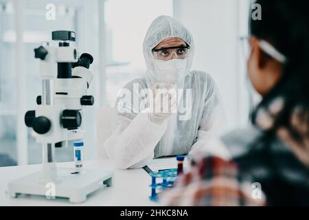 En cas de doute, consulter l'expert.Photo d'un scientifique dans le hazmat ayant une consultation avec un patient dans un laboratoire. Banque D'Images