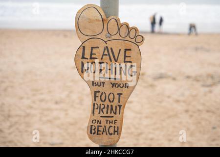 Un panneau à côté d'une plage dorée indique : « Laissez rien d'autre que votre empreinte de pied sur la plage » à Blyth South Beach, Northumberland, Royaume-Uni. Banque D'Images