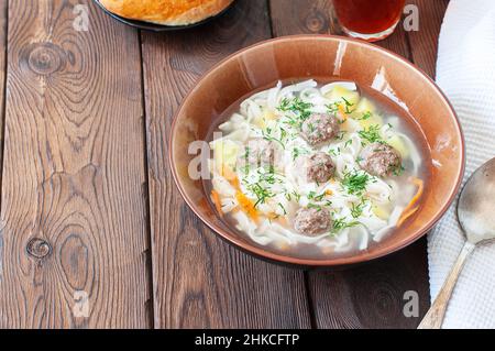 Soupe de boulettes de viande maison avec nouilles dans un bol sur fond de bois. Banque D'Images