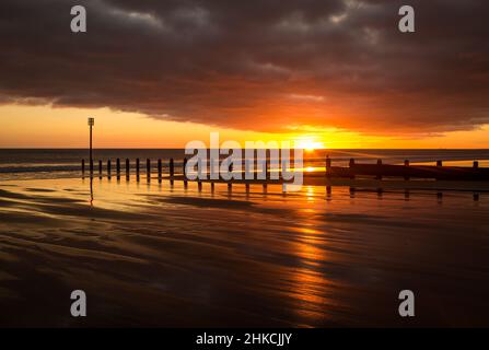 Lever du soleil pour commencer la journée à Blyth Beach dans Northumberland, avec le phare de St Mary au loin Banque D'Images