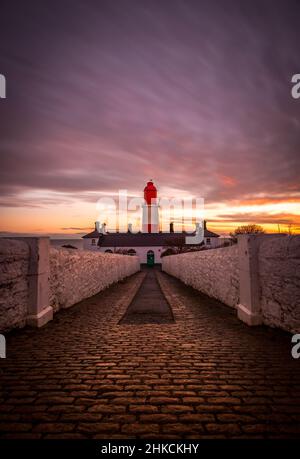 Le sentier pavé aux rayures rouges et blanches, 23 mètres de haut, le phare de Souter à Marsden, South Shields quand le soleil se lève Banque D'Images