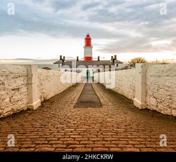 Le sentier pavé aux rayures rouges et blanches, 23 mètres de haut, le phare de Souter à Marsden, South Shields quand le soleil se lève Banque D'Images