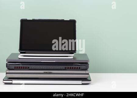 Pile d'anciens ordinateurs portables et tablette numérique utilisés pour le recyclage sur table blanche.Obsolescence planifiée, e-déchets, déchets électroniques pour réutilisation et Banque D'Images