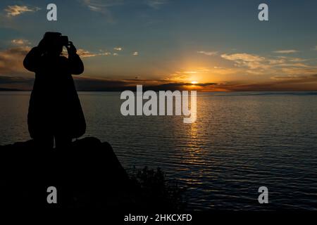 Femme prenant une photo avec coucher de soleil sur l'arrière-plan Banque D'Images