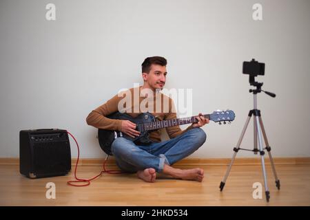 Jeune homme jouant sur une guitare devant la caméra Banque D'Images