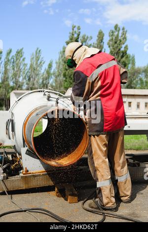 Le soudeur coupe les gros tuyaux métalliques par soudage à l'octéthylène Banque D'Images