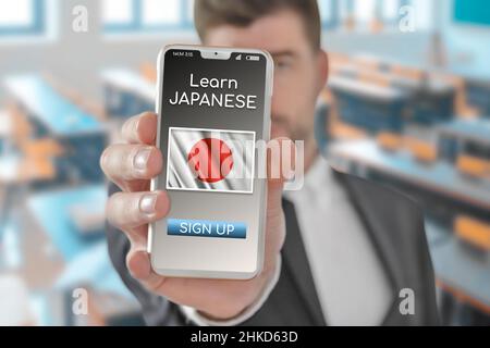 Concept en ligne Apprenez la langue japonaise avec une personne montrant l'application e-learning sur un téléphone mobile avec le drapeau du Japon Banque D'Images