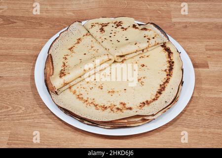 Beaucoup de crêpes fines faites maison sur une assiette blanche. Vue de dessus. Dessert sucré russe traditionnel. Crêpes délicieuses sur une table en bois. Banque D'Images
