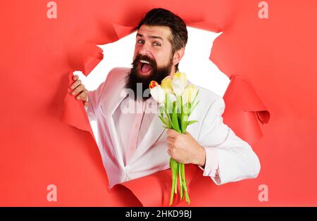 Homme heureux avec bouquet tulipes.Homme d'affaires barbu avec fleurs.Saint-Valentin ou Womens, anniversaire. Banque D'Images