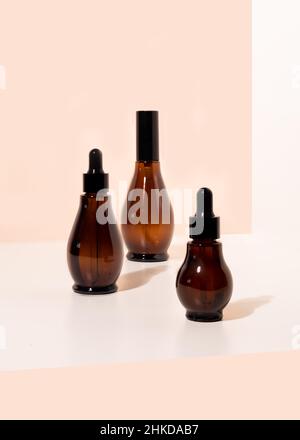 Vaporisateur en verre ambré et flacons compte-gouttes avec cosmétiques sur une table de salle de bains lumineuse. Banque D'Images