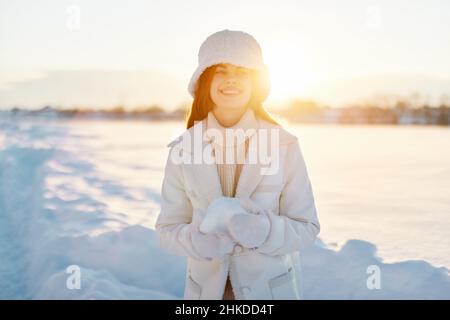 Belle femme sourire hiver humeur marche blanc manteau neige dans les mains nature Banque D'Images