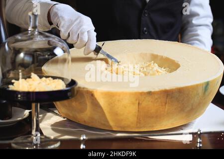 Le serveur coupe des morceaux de parmesan Banque D'Images