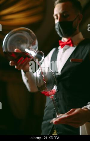 Le sommelier verse du vin dans un verre d'un bol Banque D'Images