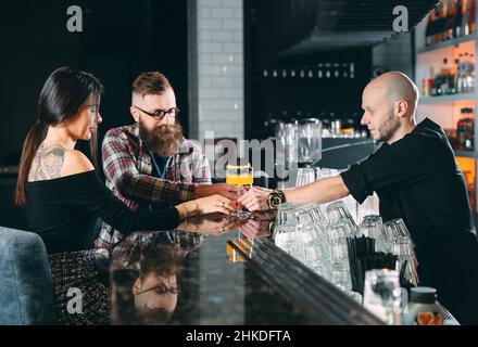 Le barman verse des cocktails à un jeune couple dans un restaurant Banque D'Images