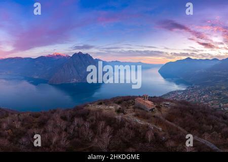 Vue aérienne de la petite église de San Defendente dominant le lac d'Iseo au coucher du soleil.Solto Collina, Lac d'Iseo, quartier de Bergame, Lombardie, Italie. Banque D'Images
