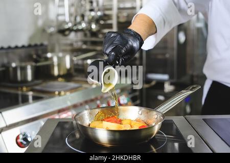 Gros plan sur les mains du chef cuisant des aliments au feu.Le chef brûle des aliments dans une cuisine professionnelle Banque D'Images