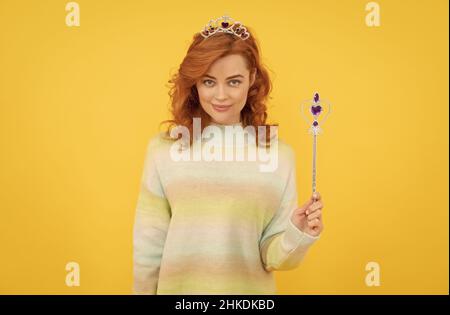 femme souriante à tête rouge dans la couronne de reine avec baguette magique, wish Banque D'Images
