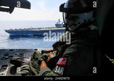 MER DE CHINE MÉRIDIONALE (FÉV1, 2022) le chef de l'équipage naval (hélicoptère) Justin Wright, de Linden, en Californie, observe le porte-avions de la classe Nimitz USS Abraham Lincoln (CVN 72) de la cabine d'un hélicoptère MH-60s Sea Hawk, affecté aux 'Chargers' de l'Escadron de combat de la mer (HSC) 14.Abraham Lincoln Strike Group est en cours de déploiement prévu dans la zone d'exploitation de la flotte américaine 7th afin d'améliorer l'interopérabilité par le biais d'alliances et de partenariats tout en servant de force d'intervention prête à l'emploi pour soutenir une région Indo-Pacifique libre et ouverte.(É.-U.Navy photo par Mass communication Specia Banque D'Images