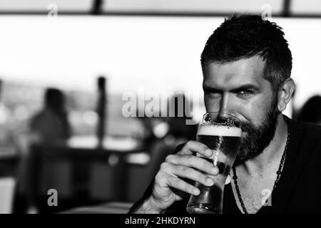 Hipster se détendre au pub.Jeune homme joyeux tenant un verre de bière et regardant la caméra. Banque D'Images