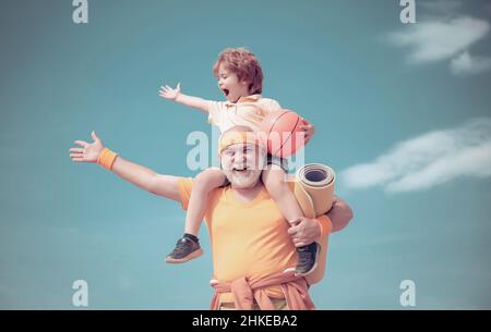 Homme âgé et mignon petit garçon s'exerçant sur fond bleu ciel - isolé.Père et fils sportifs - ensemble en famille.Faire du sport est gratuit. Banque D'Images