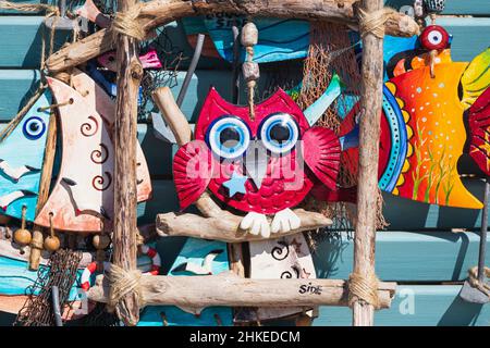 Souvenirs, figurines en argile multicolore, un chat, un hibou, des navires avec des mouettes se tiennent dans une rangée pour la vente dans un magasin Banque D'Images
