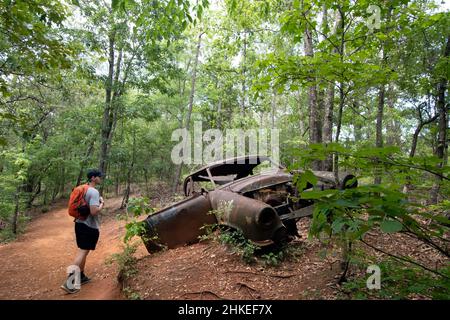 Lumpkin, Géorgie, États-Unis- 6 juin 2021 : ancienne voiture abandonnée sur le site d'une ancienne ferme avec un randonneur mâle regardant le parc national de Providence Canyon dans les s Banque D'Images