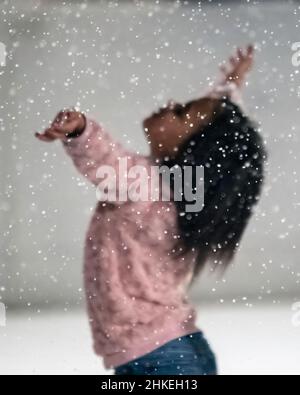 Prattville, Alabama, Etats-Unis- 23 décembre 2021: Concentrez-vous sur les flocons de neige avec une jeune fille levant les mains dans l'air hors-foyer dans l'arrière-plan Banque D'Images