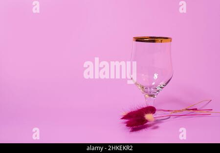 Un verre de vin vide et un bouquet de fleurs lagurus séchées Banque D'Images