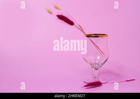 Un verre de vin vide et un bouquet de fleurs lagurus séchées Banque D'Images