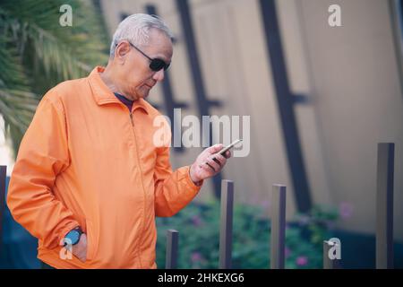 asiatique ancien homme âgé âgé âgé âgé âgé âgé âgé âgé âgé utilisant un téléphone portable mobile à l'extérieur. âge mûr retraite style de vie Banque D'Images