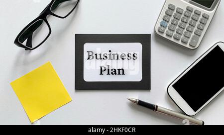 Texte du plan d'affaires sur bloc-notes avec lunettes, calculatrice, téléphone et arrière-plan de notes adhésives jaunes.Concept d'entreprise. Banque D'Images