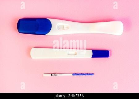 Différents types de nouveaux tests de grossesse pour femme sur fond rose clair. Banque D'Images