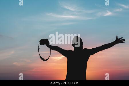 Silhouette d'un photographe sur fond de coucher de soleil avec un trépied Banque D'Images