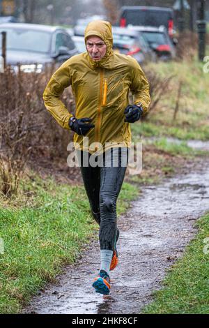 WIMBLEDON LONDON, UK. 4th Feb, 2022. A man jogging on Wimbledon Common, south west London in the cold freezing rain as the met office has forecast  a drop in temperatures and 'snow and sleet' for the south west of England  tonight Credit: amer ghazzal/Alamy Live News Banque D'Images
