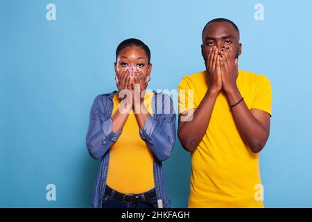 Petit ami et petite amie à la bouche ouverte en studio.Un couple frustré en état de choc a peur de quelque chose devant l'appareil photo.Terrifiée dans l'étonnement ensemble. Banque D'Images