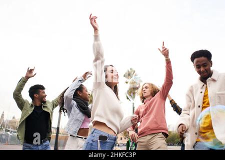 Des gens heureux dansant à l'extérieur.Groupe d'amis qui s'amusent dans une fête de jour. Banque D'Images