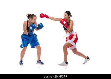 Portrait dynamique de deux boxeurs professionnels femelles en boxe isolée sur fond blanc de studio. Couple d'athlètes caucasiens en forme musculaire qui se battent Banque D'Images