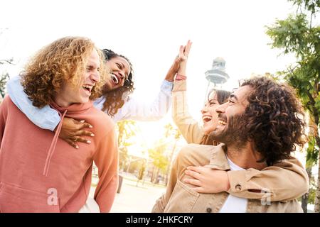 Des gens heureux.Groupe d'amis souriants célébrant donner haut cinq célébrant le succès et s'amuser ensemble dans un parc de la ville. Banque D'Images