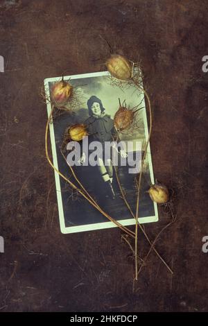 Photo studio noir et blanc de 1920s jeunes femmes assises sur ballasde avec des tiges séchées de Nigella ou d'Amour dans une brume couchée sur le dessus Banque D'Images