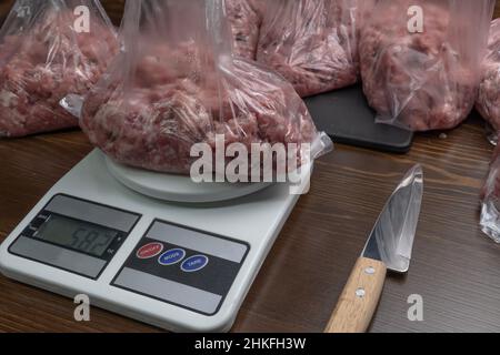 Mesurez la viande hachée sur la balance.La viande crue est divisée en portions.Cuisson.Le comptoir dans le département de la viande du supermarché.Bise de boucher Banque D'Images