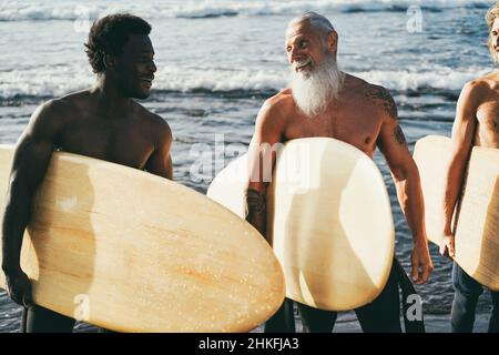 Les hommes surfeurs multigénérationnels s'amusent sur la plage - Focus sur le visage d'homme senior Banque D'Images