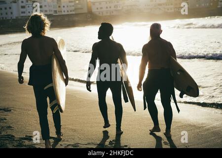 Amis surfeurs multigénérationnels s'amuser tout en surfant sur la plage - Focus sur l'homme gauche Banque D'Images