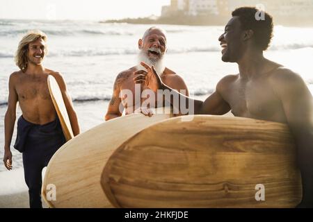 Amis surfeurs multigénérationnels s'amuser sur la plage après la session de surf - Focus sur le visage d'homme senior Banque D'Images