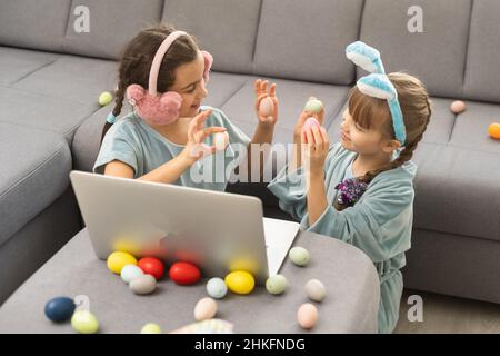 De jolies petites filles avec des oreilles de lapin faisant un appel vidéo sur un ordinateur portable. Banque D'Images