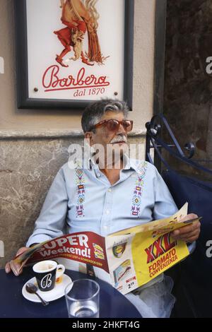 Italie, Sicile, Taormina, vieil homme sicilien avec des verres rouges et journal en main au café barbero situé sur corso Umberto dans le centre médiéval Banque D'Images