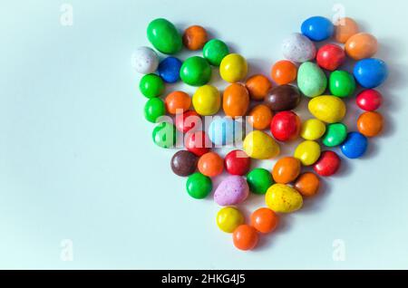 Petits bonbons multicolores en forme de cœur sur fond blanc avec espace pour écrire du texte Banque D'Images