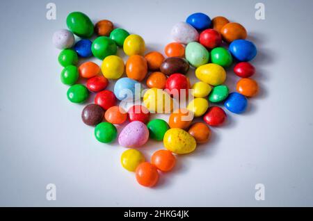 Petits bonbons multicolores en forme de cœur sur fond blanc avec espace pour écrire du texte Banque D'Images
